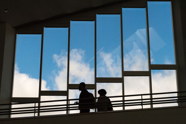 Two people silhouetted against a row of windows