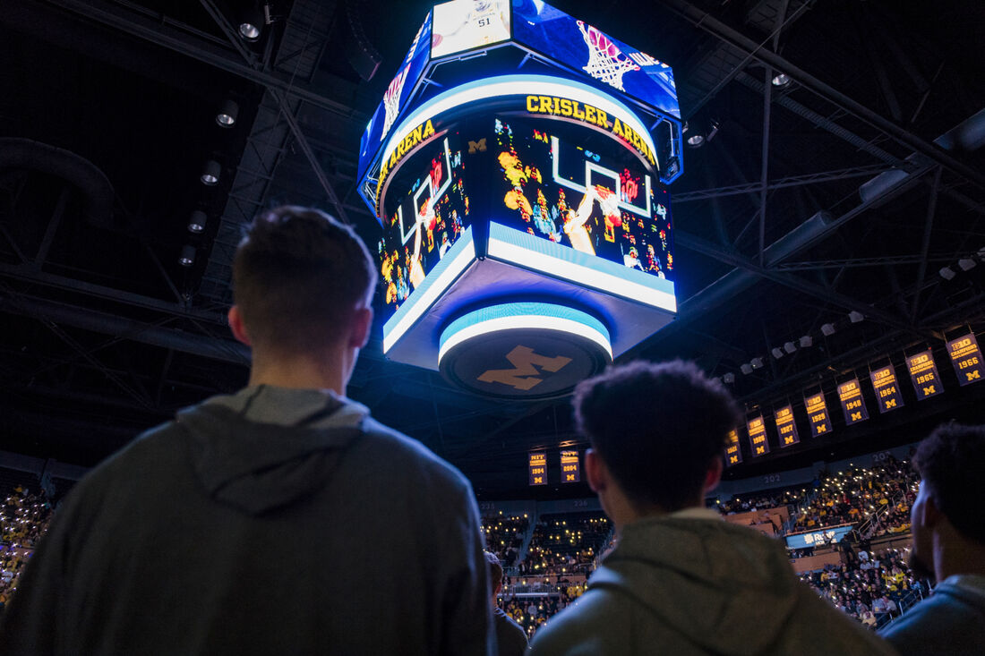 Fans looking at a jumbotron during a basketball game at Crisler