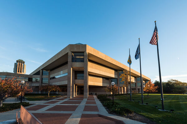 The corner of Duderstadt Center with flags in front of it at dusk