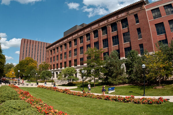 The four-story brick exterior of East Hall with flowers on the grounds on a sunny day