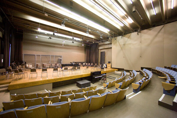 The interior of a small auditorium with many chairs on the stage
