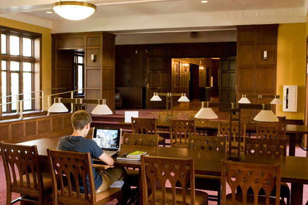 A student studying in a wood-paneled study lounge in Mosher-Jordan Hall