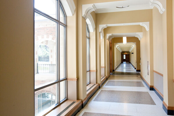 Looking down a long hallway with windows and architectural details that make small archways