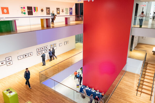 A two-story open gallery with a red wall divider in the center