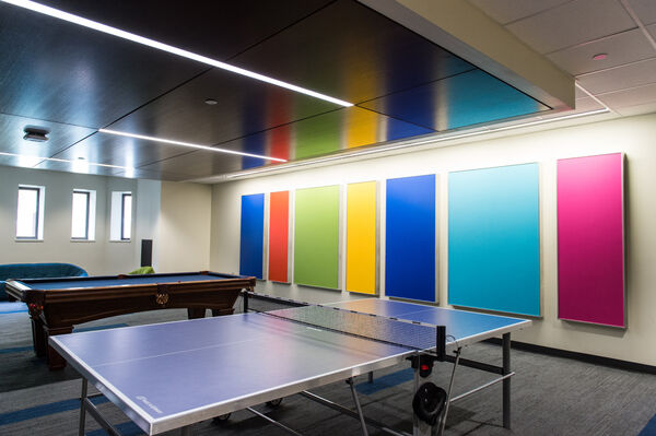 A ping-pong table in a recreation room with brightly-colored rectangular panels on the wall
